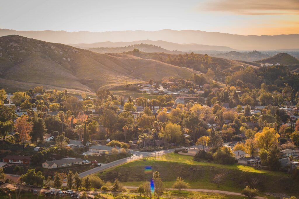 Aerial view capturing a serene countryside landscape with hills, trees, and village at sunset.